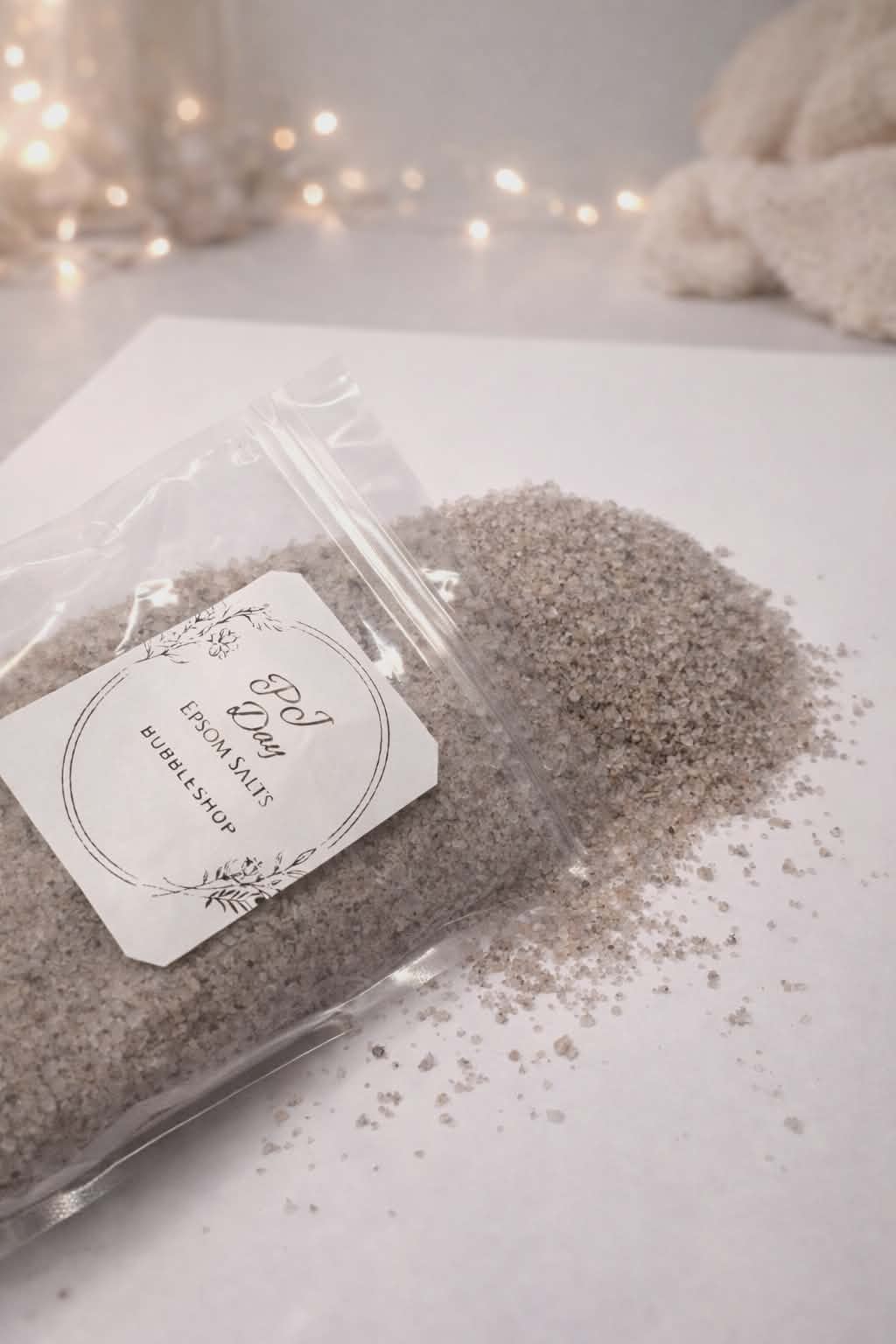 Packaged product with a label on a light surface, surrounded by soft lighting. bath salts 