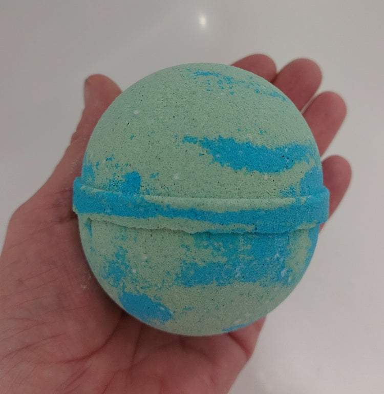 large round bathbomb in adventurous fragrance in blue and green held in hand to show size by BubbleShop