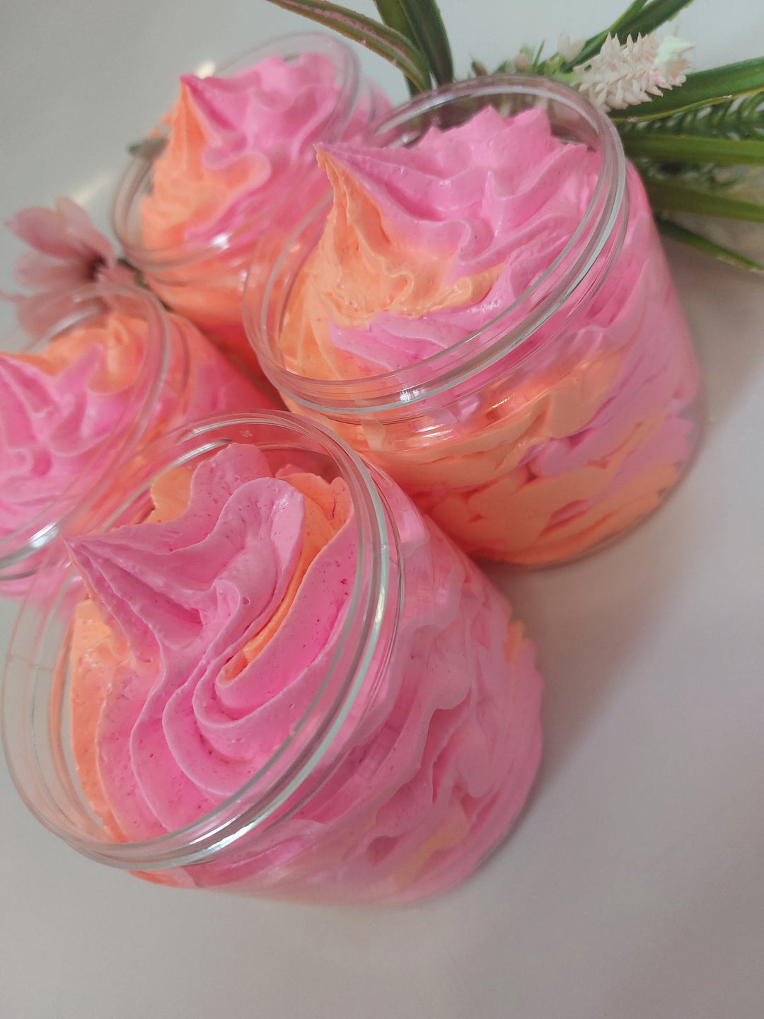 side photo of 4 whipped soap in pink and orange showing texture and piping by BubbleShop  in a perfume inspired fragrance  