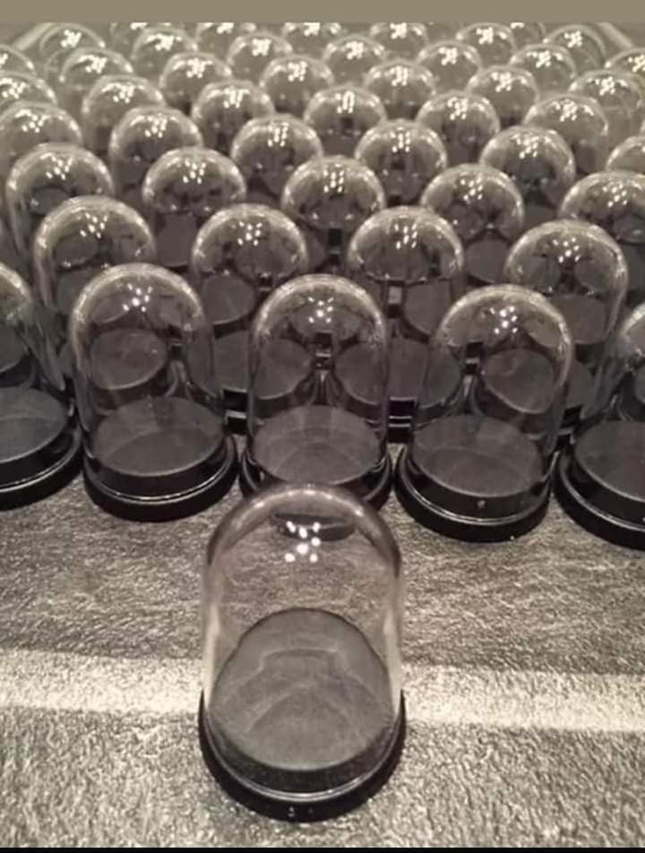 A collection of clear and black miniature plastic domes arranged in rows on a grey surface.